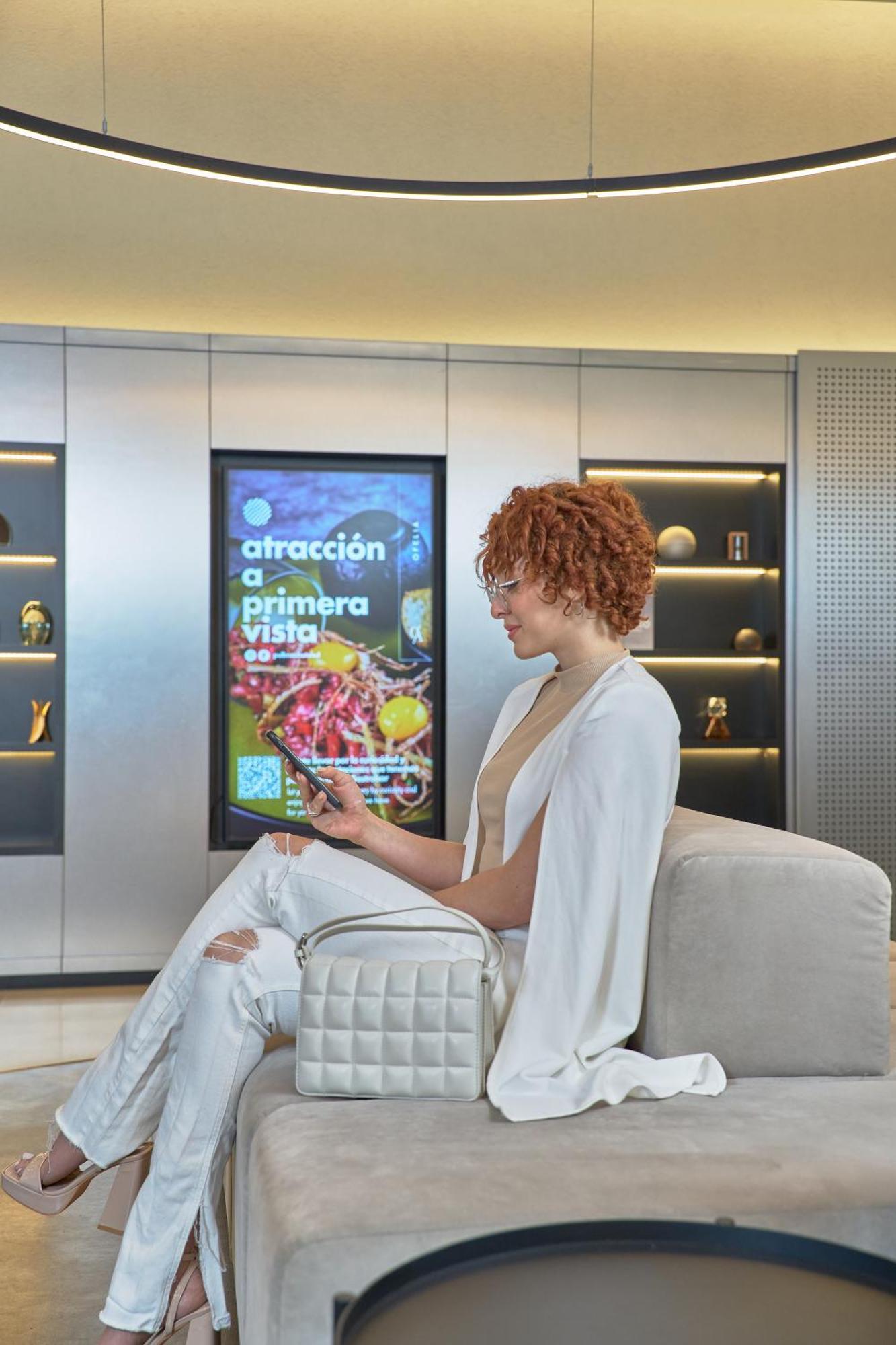 Pullman Santiago Vitacura Bagian luar foto A woman using a mobile phone to interact with a digital signage display