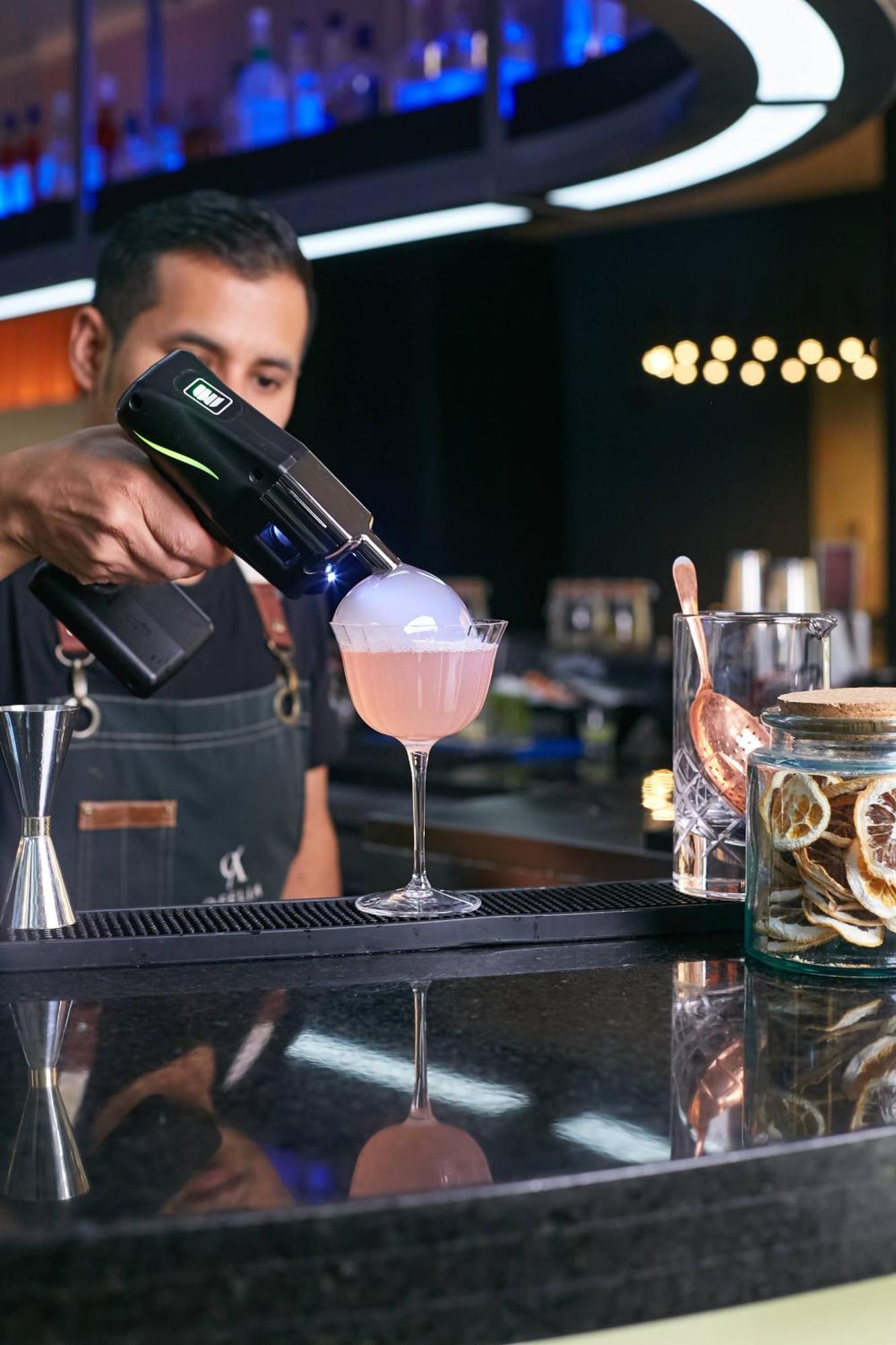 Pullman Santiago Vitacura Bagian luar foto A bartender using a blowtorch to cook a cocktail